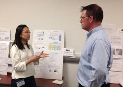 Ph.D. student Di Yang explains her work to Dr. Lee Eric Dashofy, The Aerospace Corp. at Open House.